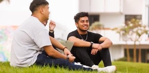 two students sit on the mounds and look off into the distance